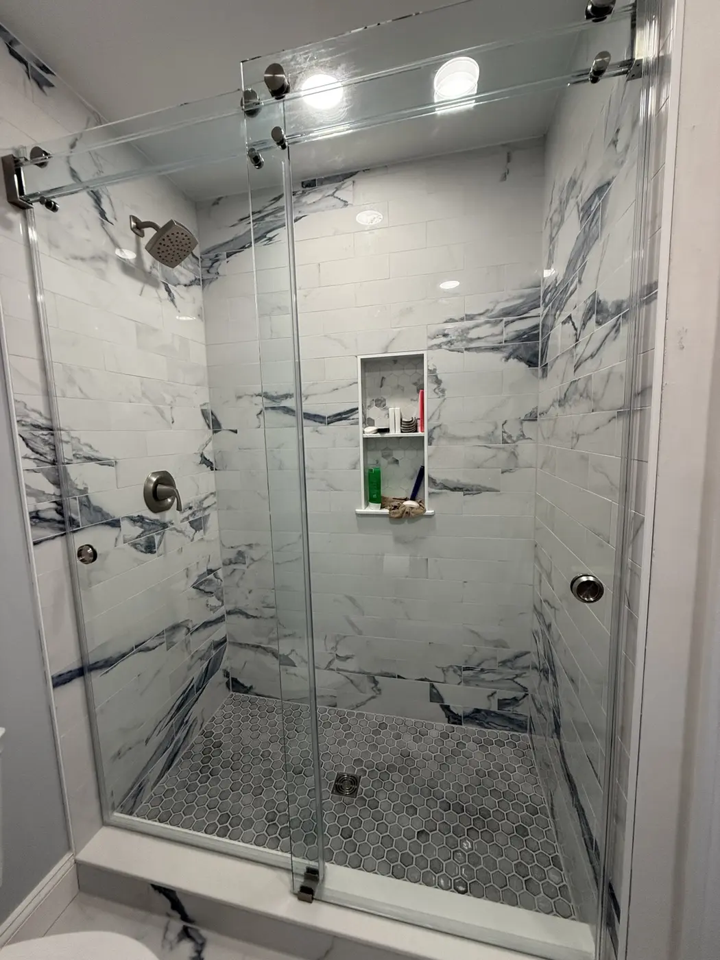 Blue and white marble-look tiled shower with glass doors