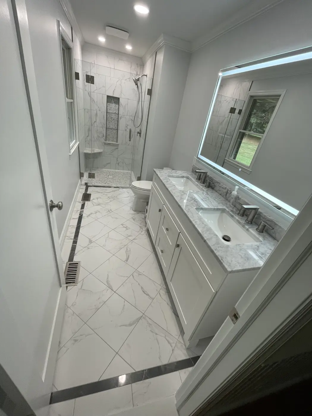 Bright marble-look bathroom with glass shower