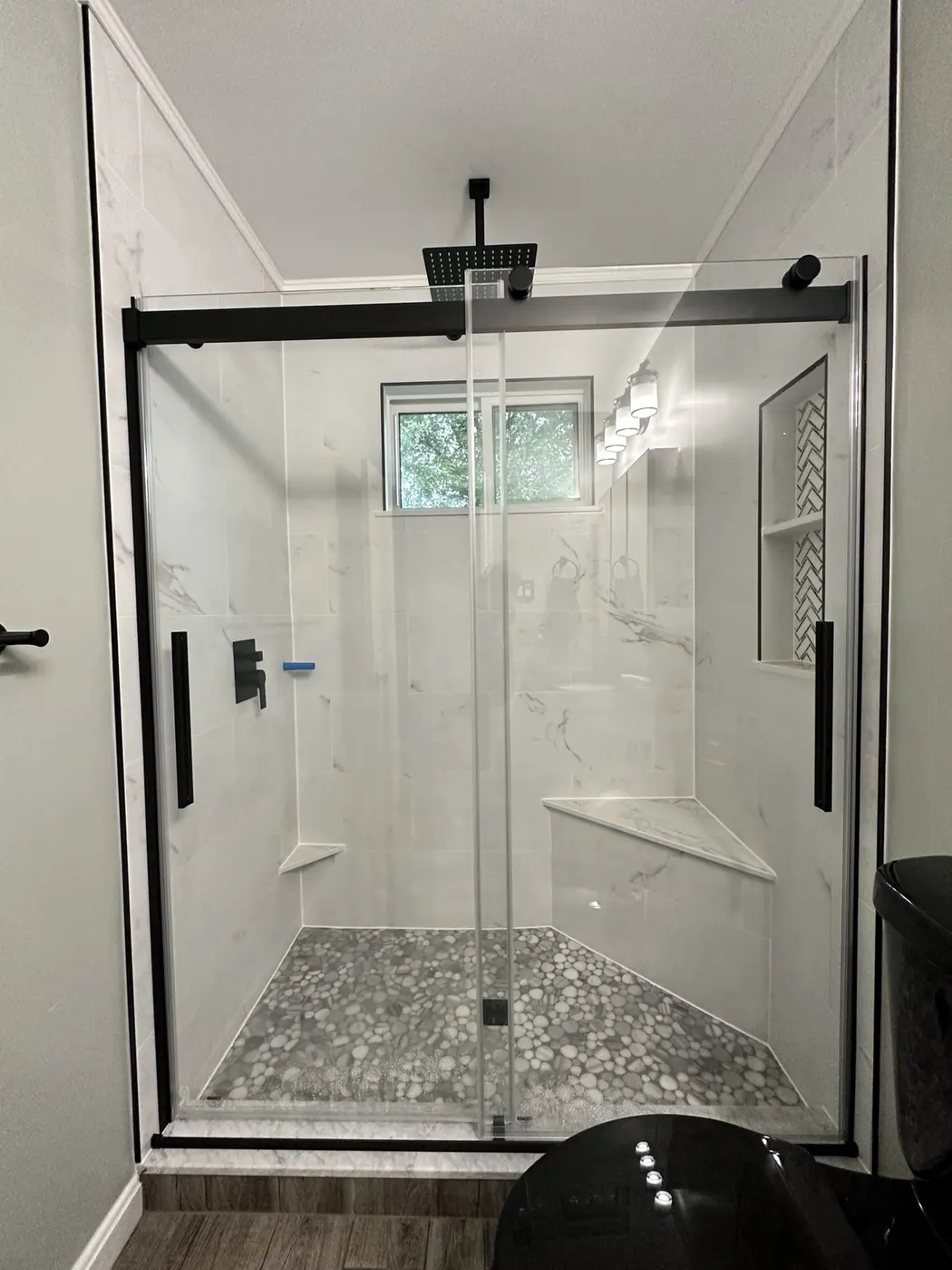 Walk-in shower with black-framed glass and pebble floor